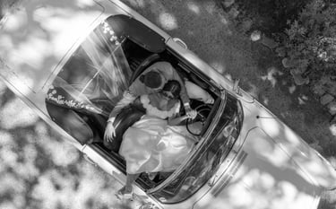 Photo aérienne de jeunes mariés dans une voiture décapotable vintage lors d'un mariage élégant
