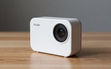 A close-up photograph of a sleek white Ajax MotionCam and a Hub placed on a minimalist wooden surface. The lighting is soft and natural, reflecting a modern reliability. Touches of soft sage and dark slate grey are present in the background.