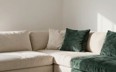 An organized living room corner in Spain / Latin America showing clean architectural lines, warm natural light, soft textured fabrics in off-white and deep slate green, reflecting mental clarity and balance.