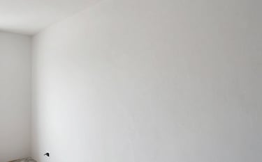 Interior view of a modern renovation in France. The focus is on a perfectly smooth white plastered wall and high-end finishing work. The lighting is soft and professional, showing off a clean, trustworthy craftsmanship.