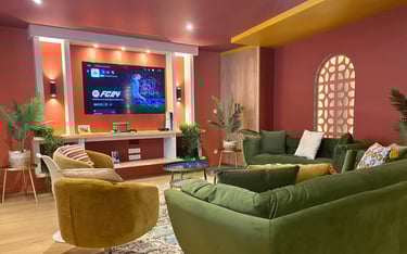Salon de maison meublée avec canapés confortables et TV murale pour professionnels en séjour.