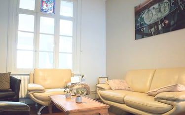 Salon lumineux de logement meublé avec canapés confortables et table basse en bois.
