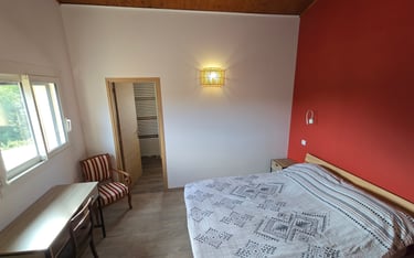 Vue de la chambre d'hôtes depuis la porte d'entrée, avec lit double, bureau et chaise.