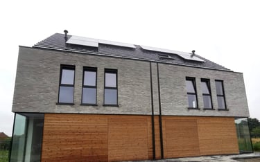 Een huis met een dak met zonnepanelen en een houten omheining.