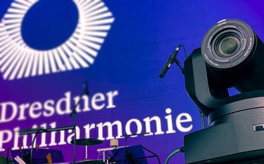 Professionelle Videokamera auf Bühne mit Giesinger Harmonie-Logo.