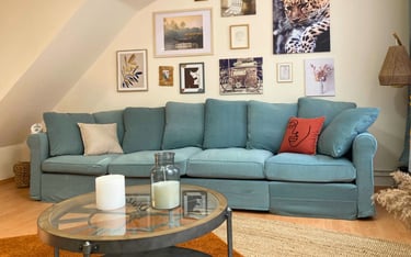 Salon décoré avec canapé bleu et murs ornés de cadres dans logement meublé.