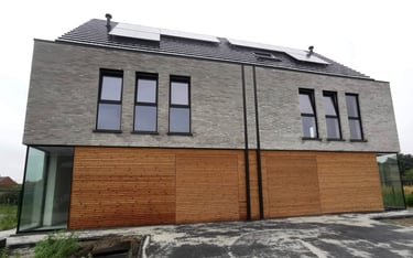 Een huis met een dak met zonnepanelen en een houten omheining.