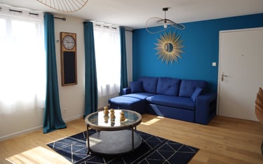 Salon lumineux avec canapé bleu et déco moderne dans logement meublé pour pros.