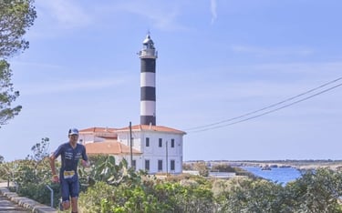 a man running on a path with a lighthouse in portocolom