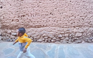 Child running in front of an earthen wall in ksar Amgrou (Zagora) southern Morocco