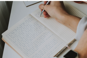 woman's hand writing in notebook