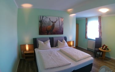 Modern hotel bedroom featuring a double bed, deer wall art, and ambient bedside lighting.