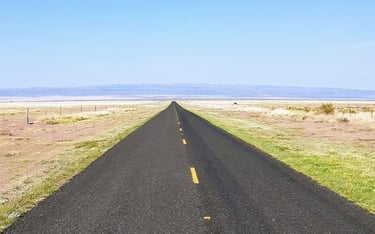 Isolated two-lane road converging at mountains in distance