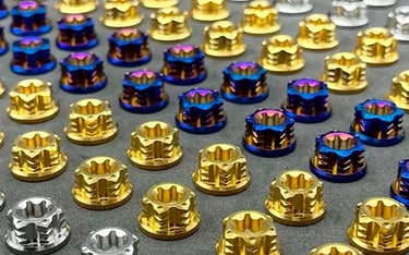 Collection of precision titanium fasteners in various grades and finishes including gold, blue, and