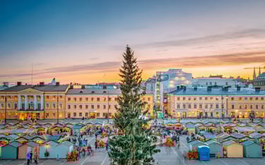 Festive Helsinki Christmas Market at Senate Square with a tall tree and sunset city views.