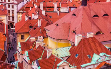 Aerial view of historic red tiled roofs and narrow cobblestone streets in Prague's Old Town.