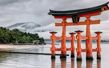 The floating Itsukushima Shrine torii gate in Miyajima, Japan, under a cloudy sky.