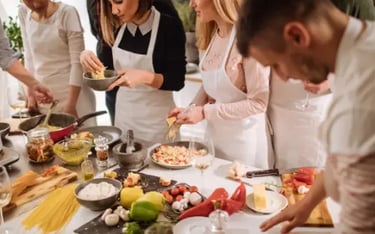 Group of people wearing aprons cooking Italian pasta during a hands-on culinary workshop.