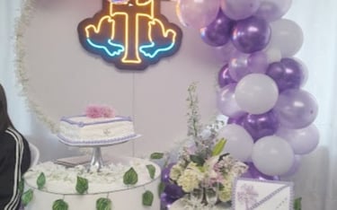Decoración de bautizo con globos morados, pastel y cruz luminosa para Zoe.