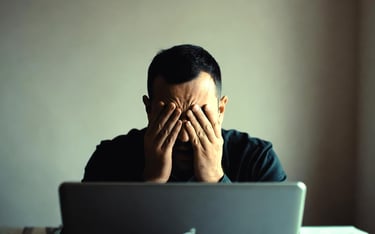 Christian man in distress at laptop struggling with porn addiction and shame.