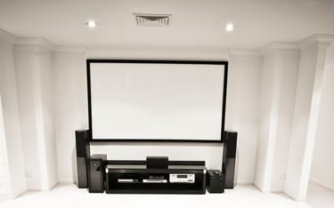 A modern entertainment setup with a wall-mounted projection screen, speaker system.