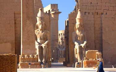 a woman in a blue dress standing in front of a large statue