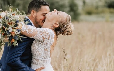 une mariée et un marié s'embrassant dans un champ