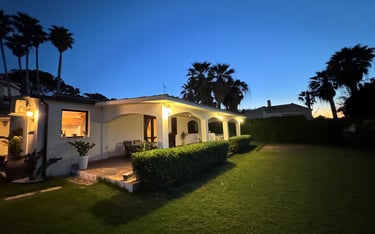 Luxury beachfront villa in Siracusa, Sicily at sunset with palm trees and manicured garden