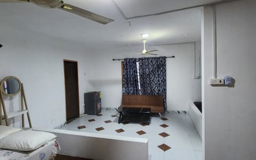 Studio apartment interior with a brown sofa, tiled floor, white walls, and a ceiling fan.