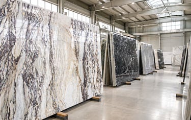 Large polished marble and granite slabs displayed in a bright industrial stone warehouse.