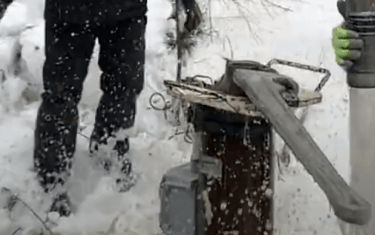 Large wrench opening well head in winter.