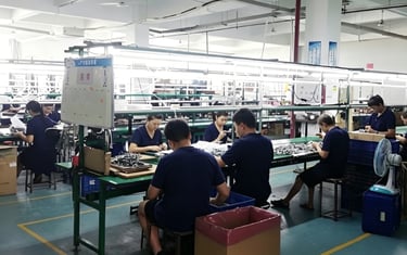 Factory workers in blue uniforms assembling nathroom ware,showers on an industrial production line.