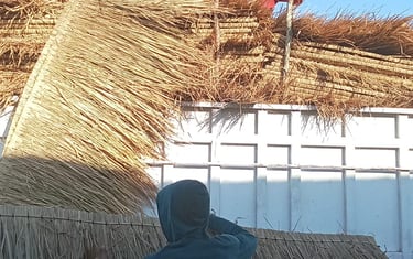 a man and woman working on a straw - woven roof