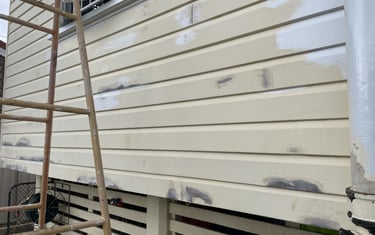 Exterior wall preparation in Zillmere showing patched weatherboards before repainting