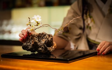 a woman dressed in kimono arranging an ikebana flower arrangement