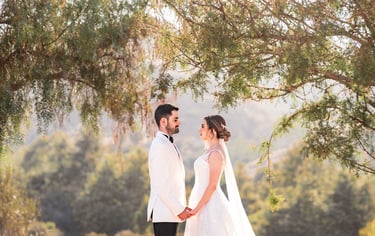 a bride and groom standing in front of a tree
