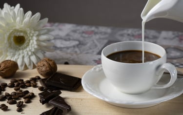 Milch wird eingegossen, Schokolade & Nüsse bereitgelegt. Detailaufnahme für metta-macro