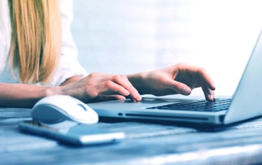 Une femme blonde pianote sur le clavier de son ordinateur portable