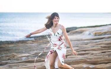 a woman in a floral dress running on a rocky beach