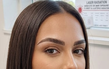 Close-up of a woman with professionally microbladed eyebrows showcasing precise hair strokes and shaping.