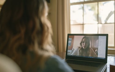A woman participates in a remote video conference call on her laptop at home.