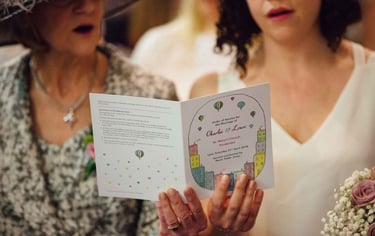 Two women holding an order or service and singing.