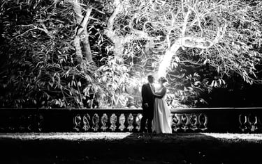 a bride and groom standing on a bridge over looking at the water