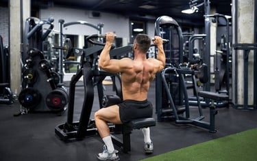 Muscular man performing back exercises on a lat pulldown machine in a modern gym.