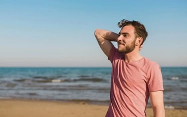 Un homme se tient sur la plage, dans une posture exprimant confiance et liberté.