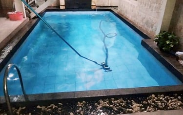 Teknisi membersihkan kolam renang menggunakan alat khusus
