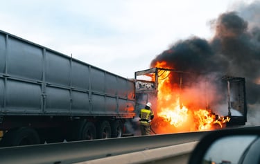 Truck and Commercial Vehicle Crashes showing a large truck on fire after a highway accident, with firefighter responding to t