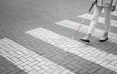 Blind person walking through city with white cane