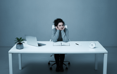 a woman sitting at a desk with a laptop and a clock