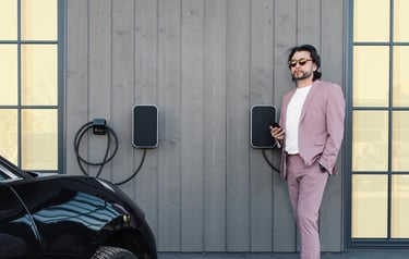 Laimingas elektra varomų automobilių krovimo stotelių savininkas žvelgia ir skaičiuoja santaupas